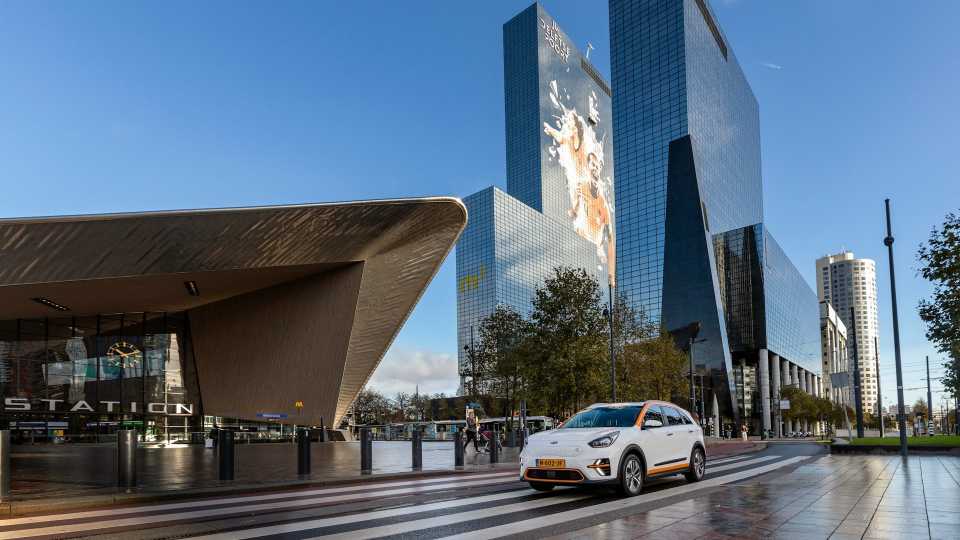 A car drives down a street in front of a building, showcasing urban scenery and everyday life.