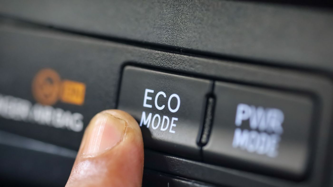 A person pressing the eco mode button inside a car, promoting fuel efficiency and environmentally friendly driving.