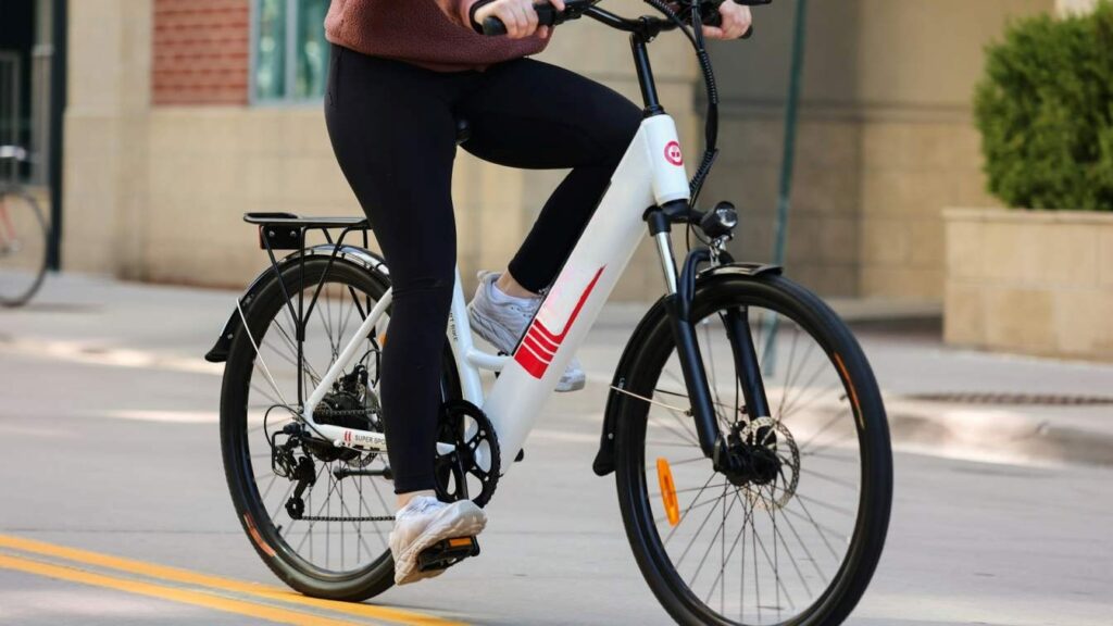 a gay having brown shirt and black pant riding electric bicycle on the roadside of the building