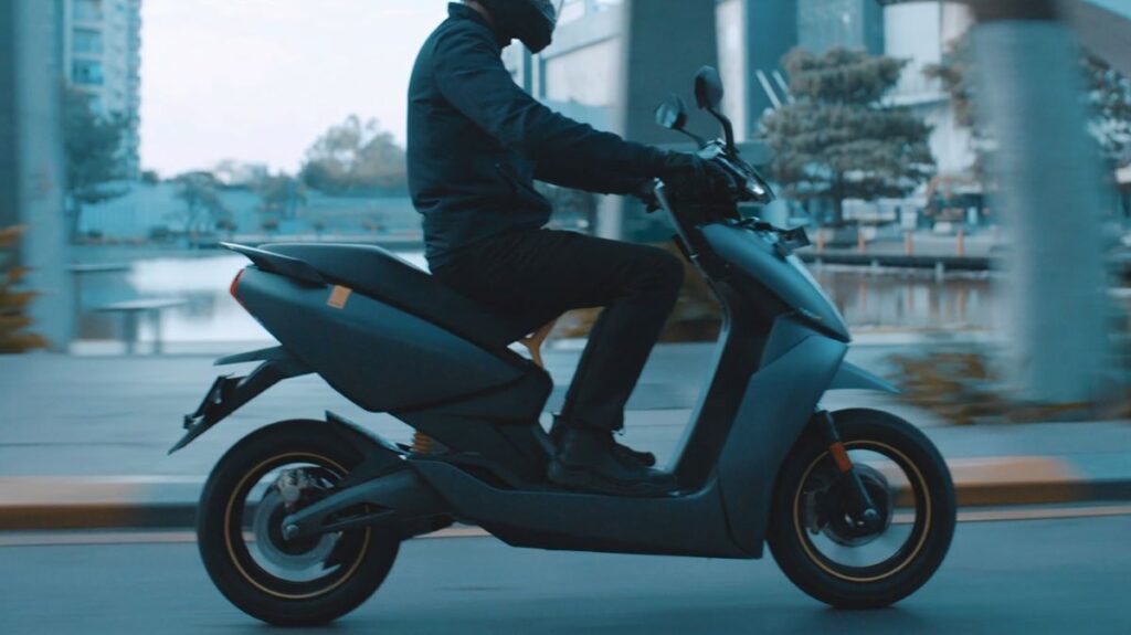 Person riding a modern electric scooter, highlighting models with removable batteries.